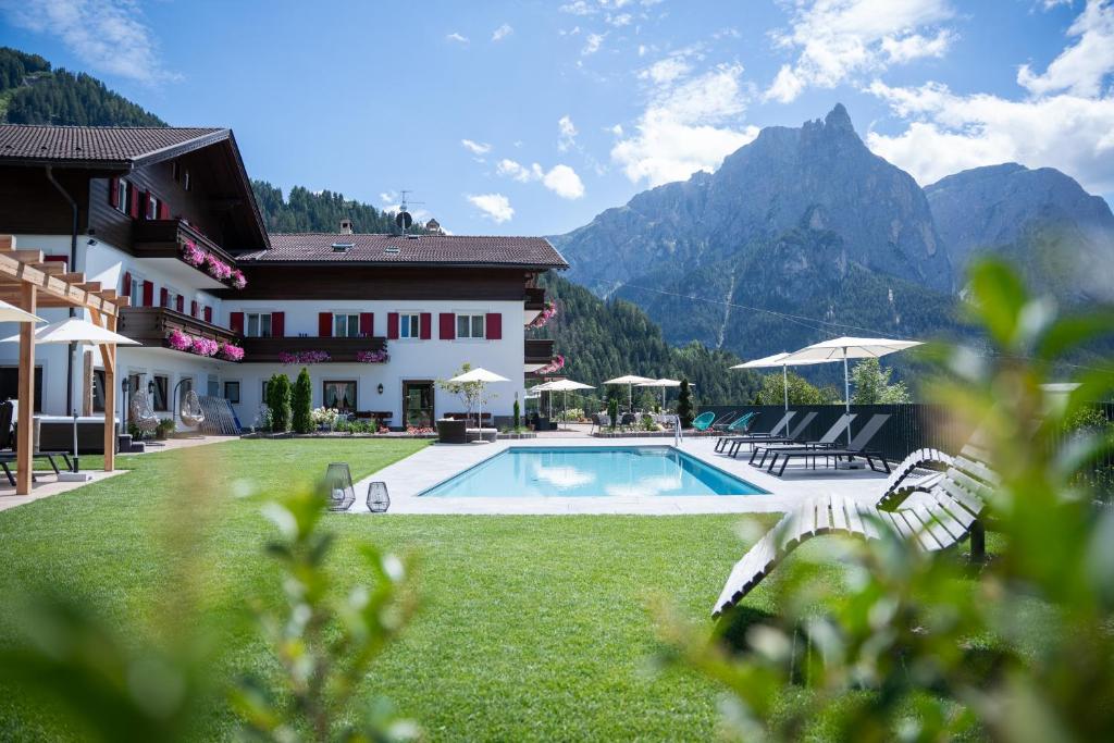 a resort with a swimming pool and mountains in the background at Hotel Ortler in Castelrotto