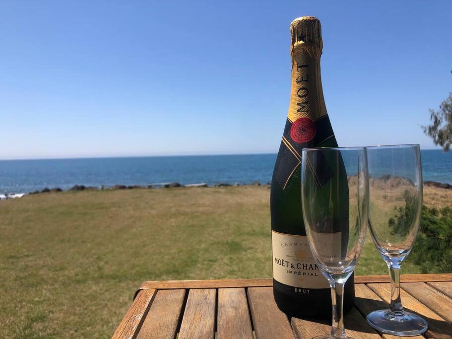 eine Flasche Champagner und zwei Weingläser auf dem Tisch in der Unterkunft Pet & Family Friendly Ocean Front Beach Cottage in Bargara