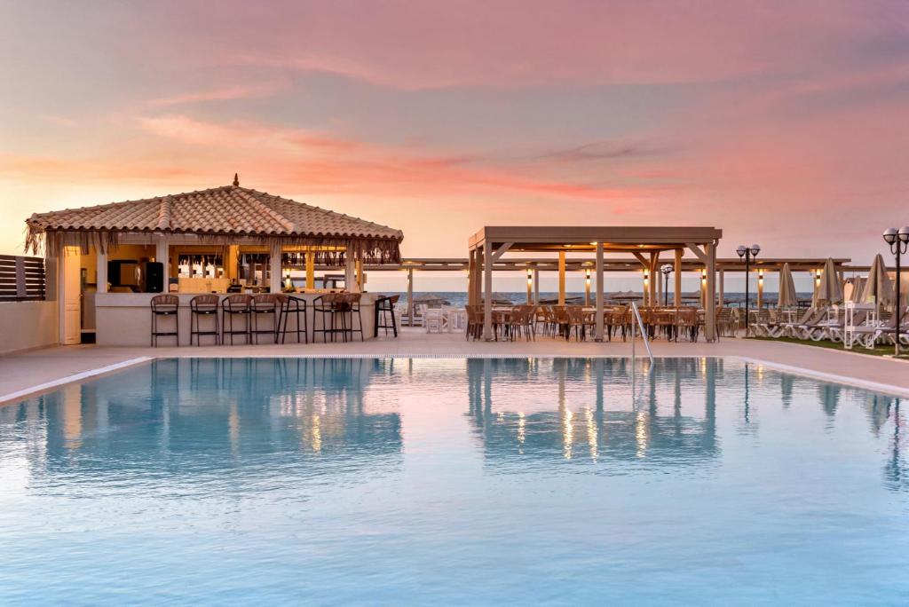 una piscina del complejo con mesas y sillas y un cenador en Neptuno Beach Hotel, en Amoudara Herakliou