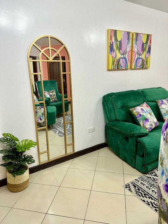 a living room with a green couch and a mirror at Cozy Retreat Near Nairobi National Park, Giraffe Centre & Wilson Airport in Nairobi
