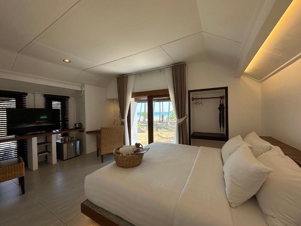 1 dormitorio con 1 cama blanca grande y TV en Chumphon Cabana Resort en Chumphon