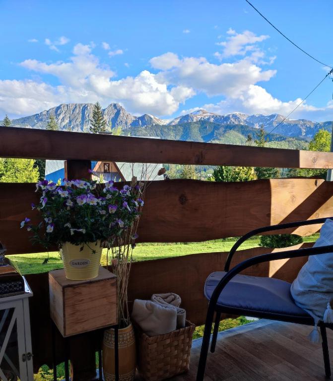 a porch with a vase of flowers and mountains at Mały Bystry Domek in Kościelisko
