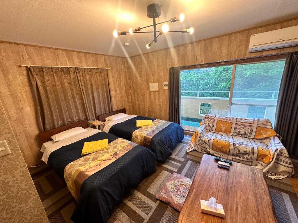 a room with two beds and a table in it at 100泊で完成する民泊 in Takamori