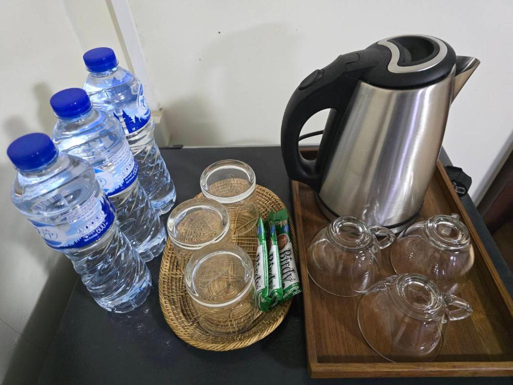 a tea kettle and glasses and bottles of water on a table at Chanida home in Phra Nakhon Si Ayutthaya