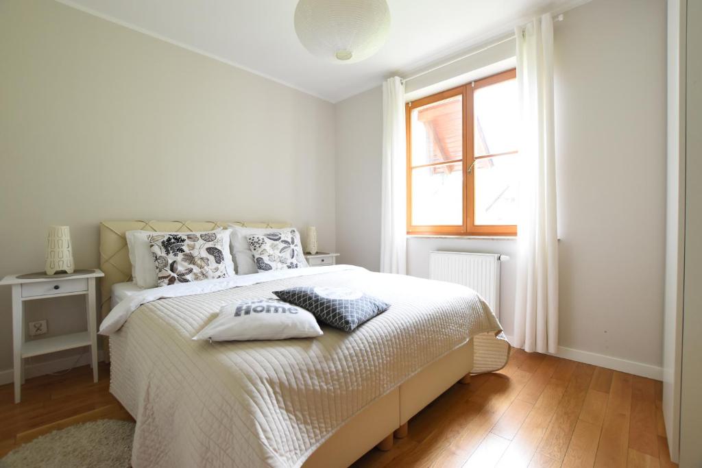 een witte slaapkamer met een bed en een raam bij SkiApartment - Apartamenty Pod Śnieżką in Karpacz