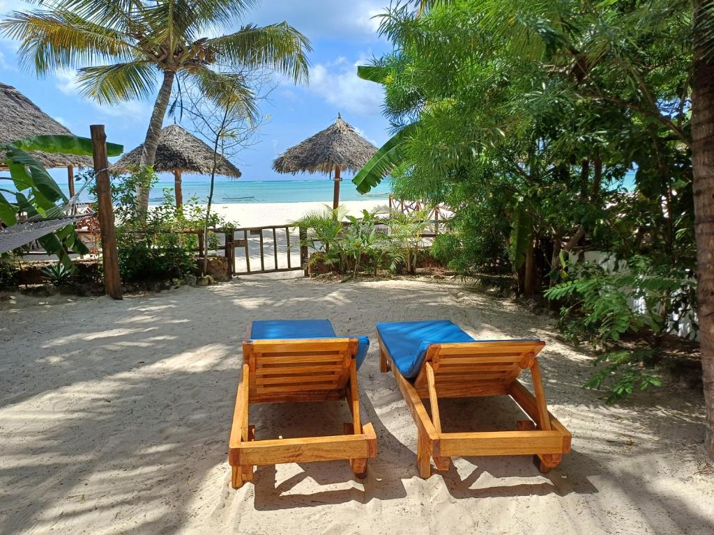 two chairs and a table on a beach at Namayani apartment in Pwani Mchangani