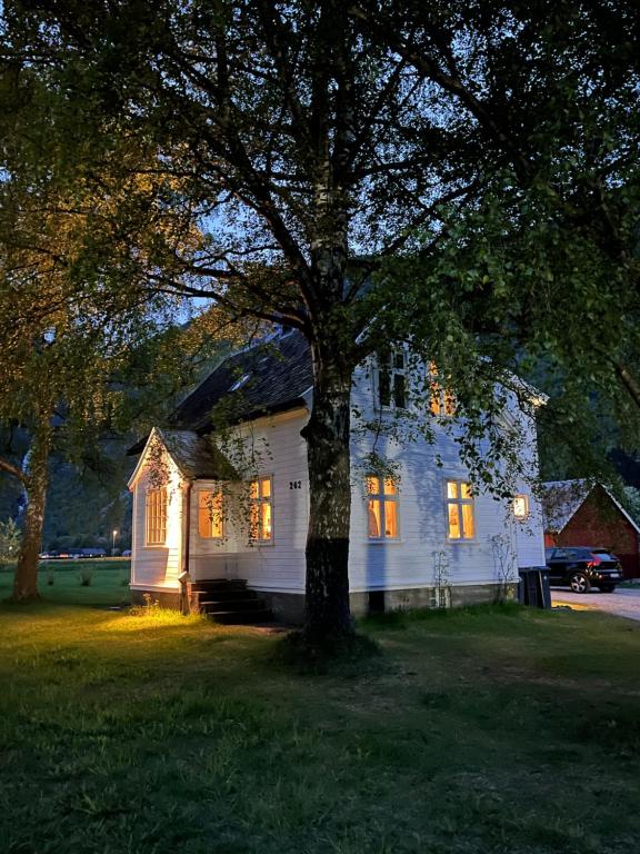 una casa bianca con un albero in cortile di Hagusane Feriehus a Lærdalsøyri