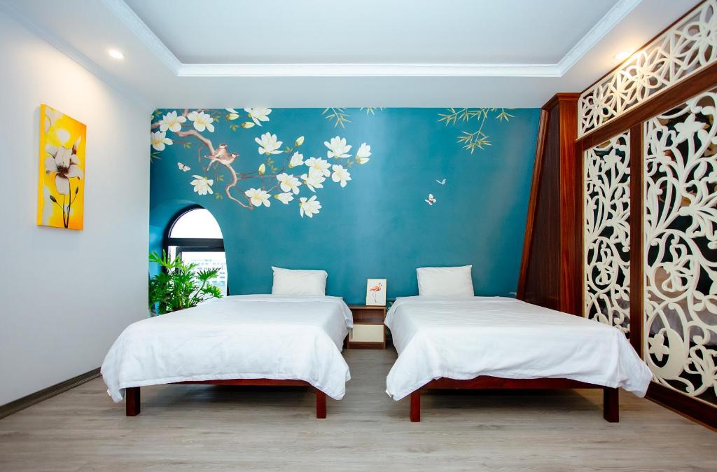 twee bedden in een kamer met een blauwe muur bij Song Anh Hotel Tuần Châu in Ha Long