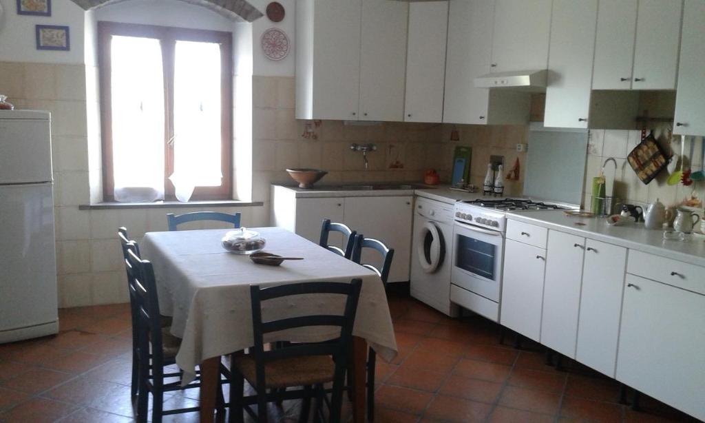 a kitchen with a table and chairs and a kitchen with white cabinets at B&B Poderone in Querceto