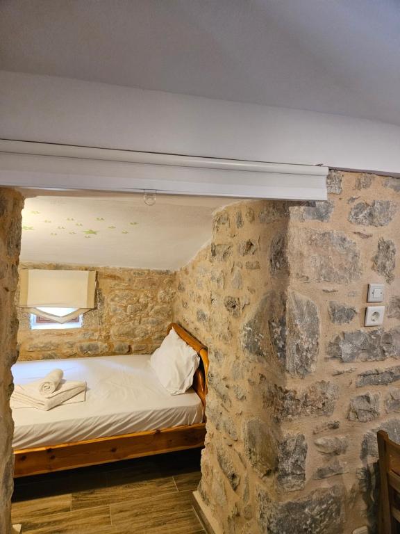 a bed in a room with a stone wall at Kamares Stone House 2 in Gerolimenas