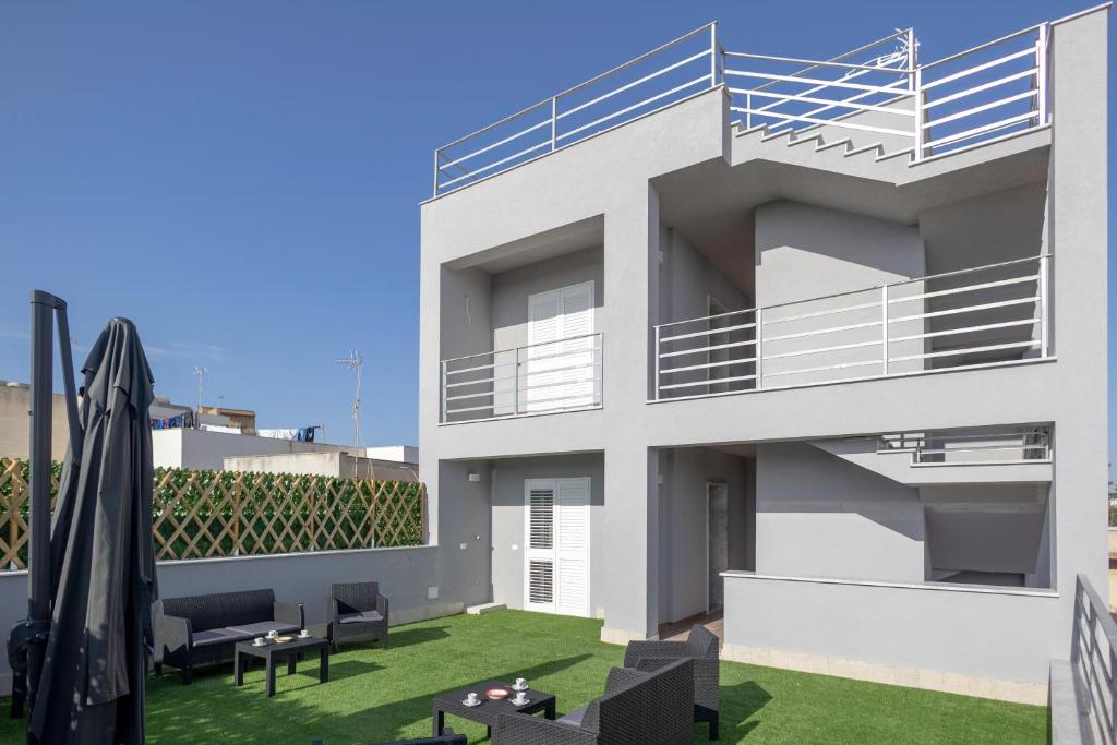 a white house with a balcony with a lawn at Elysium B&B in Mazara del Vallo