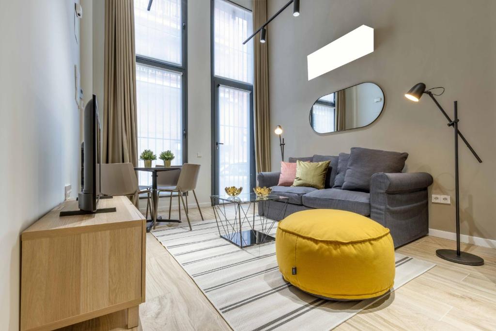 salon z kanapą i żółtą otomaną w obiekcie Castilla en Madrid w Madrycie