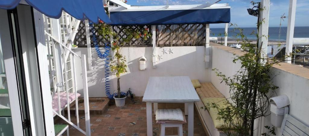 a balcony with a table and a blue umbrella at Duplex ático con las mejores vistas de Conil in Conil de la Frontera