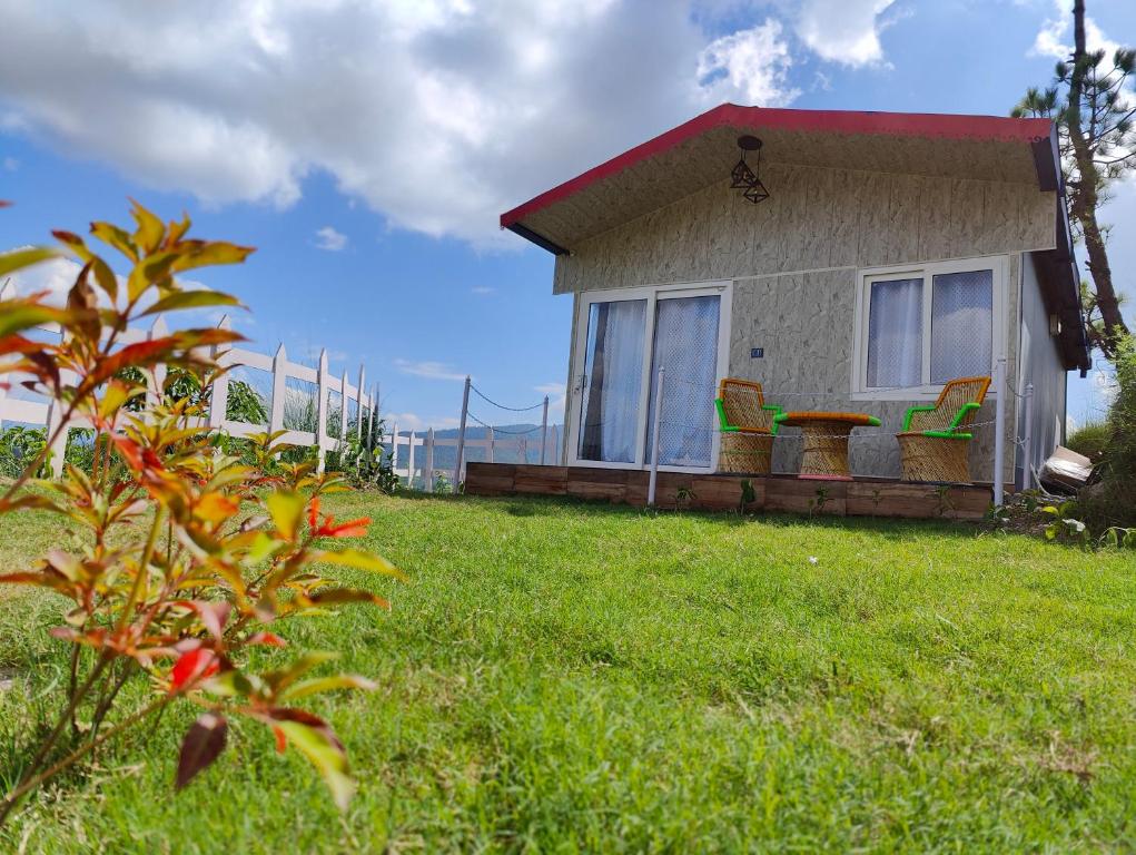 a house with chairs and a table in the grass at Adaara Retreat - Pet Friendly Cottages, Almora in Almora