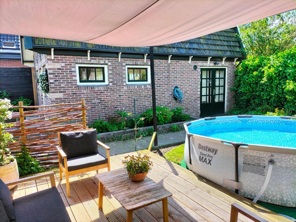 um pátio com uma piscina, uma cadeira e uma banheira em De oude walnoot em Sint Pancras