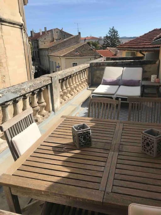 une table et des chaises en bois sur un balcon dans l'établissement Grand appartement en maison de ville, à Valréas
