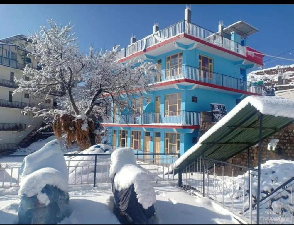 un bâtiment bleu avec de la neige au sol dans l'établissement Mcleodganj Diaries Homestay, à Dharamshala