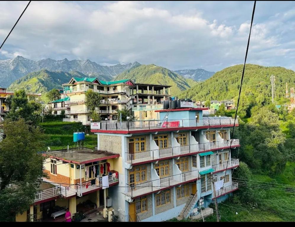 un grupo de edificios con montañas en el fondo en Mcleodganj Diaries Homestay, en Dharamshala