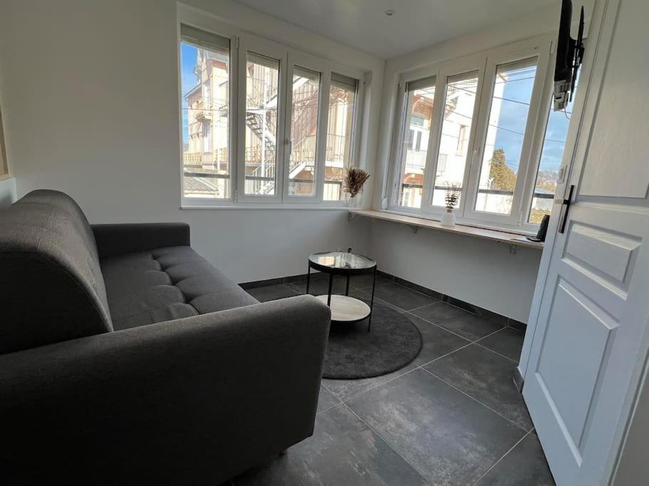 un salon avec un canapé et deux fenêtres dans l'établissement Studio Berck , proche plage , phare , centre ville, à Berck-sur-Mer