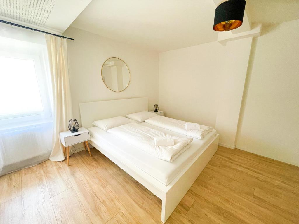ein weißes Bett in einem Zimmer mit Fenster in der Unterkunft StayHere Central City Suite 1 - contactless Self-Check-IN in Graz
