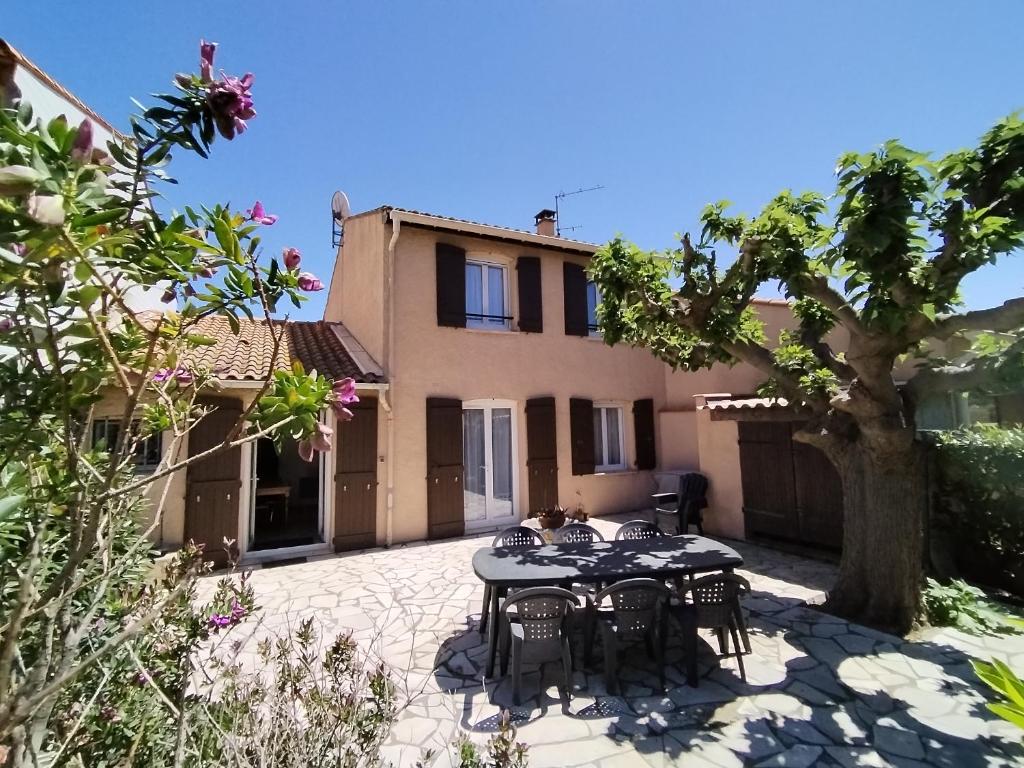 un patio avec une table et des chaises devant une maison dans l'établissement MAISON climatisée 6/8 PERSONNES 1300M DE LA PLAGE AVEC NAVETTE OU PISTE CYCLABLE, à Argelès-sur-Mer