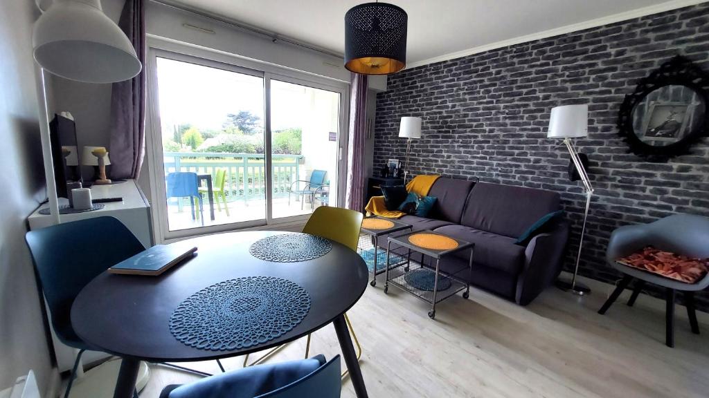 een woonkamer met een tafel en stoelen en een bank bij La Baule, studio cosy. Quartier Jumping/Atlantia in La Baule