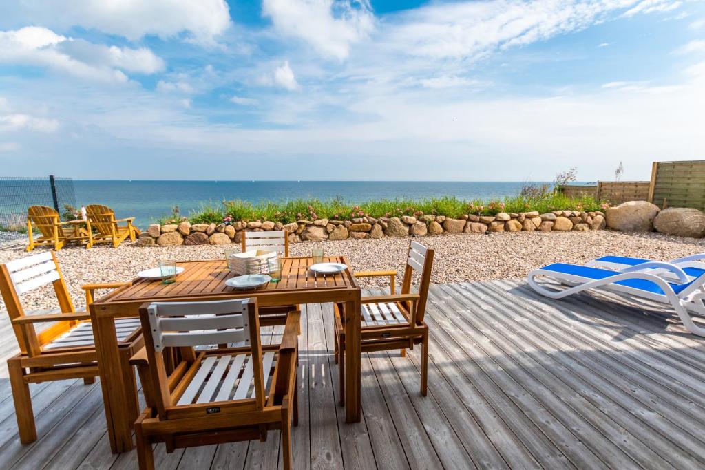 a wooden table and chairs on a deck with the beach at Haus Seaside-Dahme in Dahme