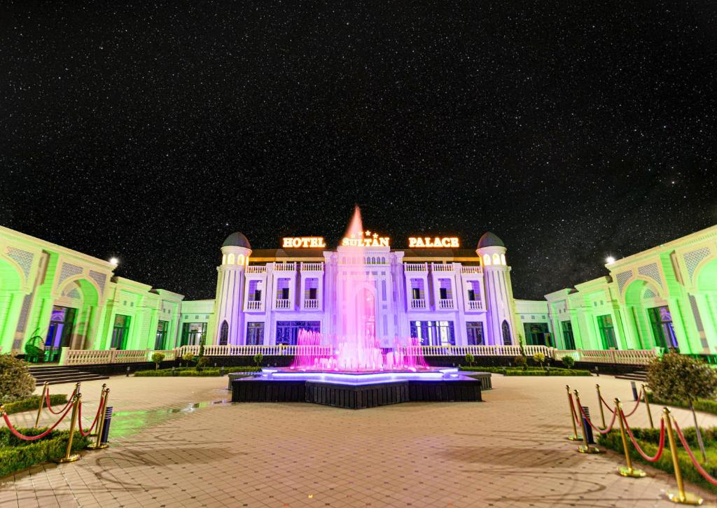 un edificio con una fuente delante de él por la noche en HOTEL SULTAN PALACE, en Samarkand