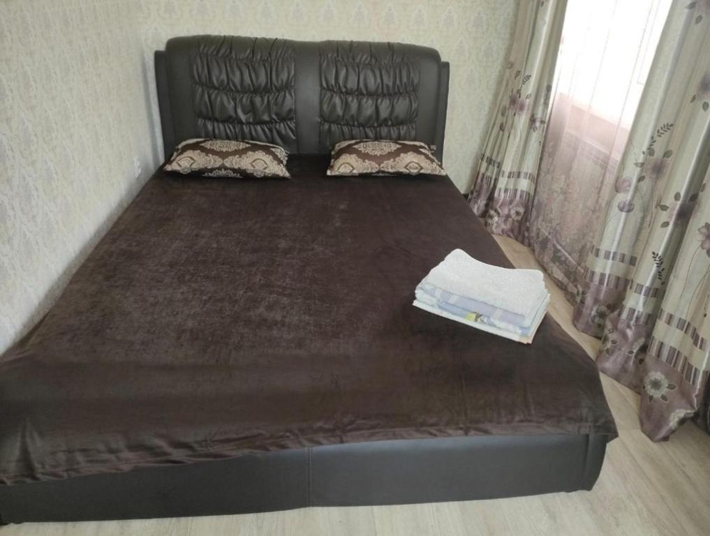 - un lit dans une chambre avec un cadre noir dans l'établissement Уютная двухкомнатная квартира в Актобе, à Aqtöbe