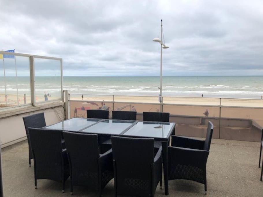 une table et des chaises avec vue sur la plage dans l'établissement Appartement 85 m2 front de mer grande terrasse magnifique vue panoramique, à Dunkerque