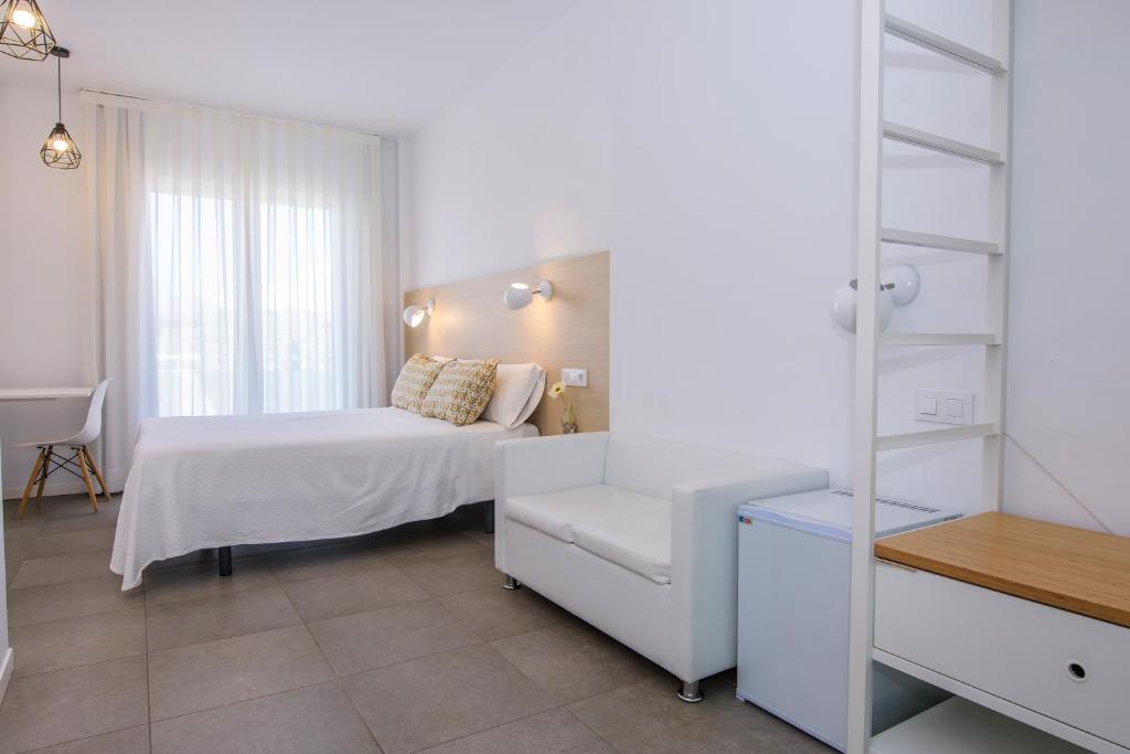 a white bedroom with a bed and a chair at Hostal La Isla in Carboneras