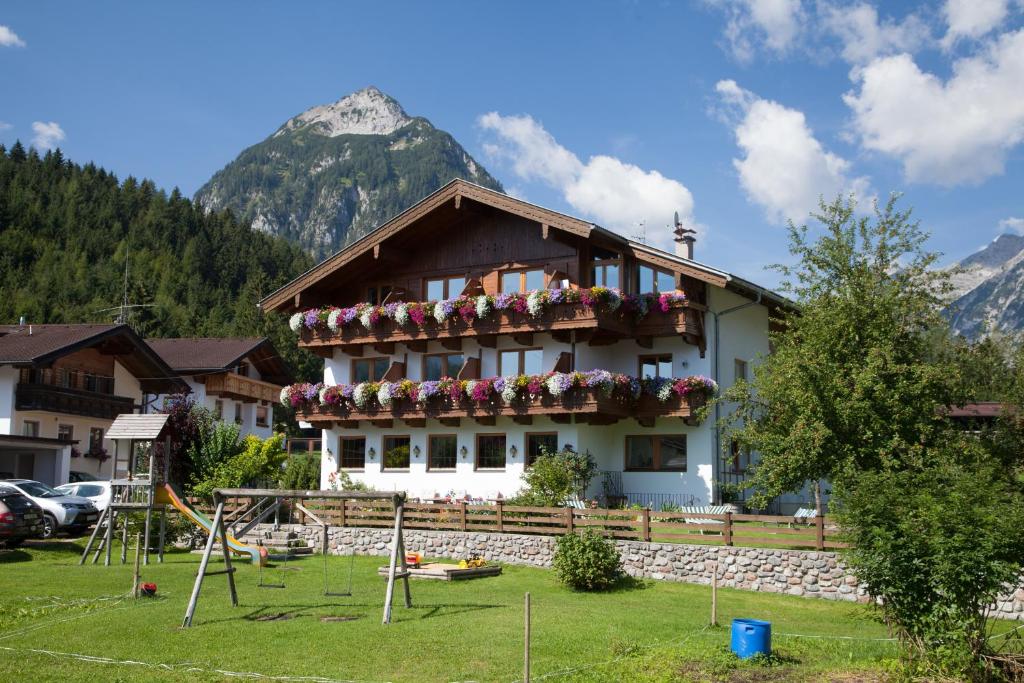 a building with flowers on the balcony with a mountain at Gasthaus-Pension Golfvilla in Pertisau