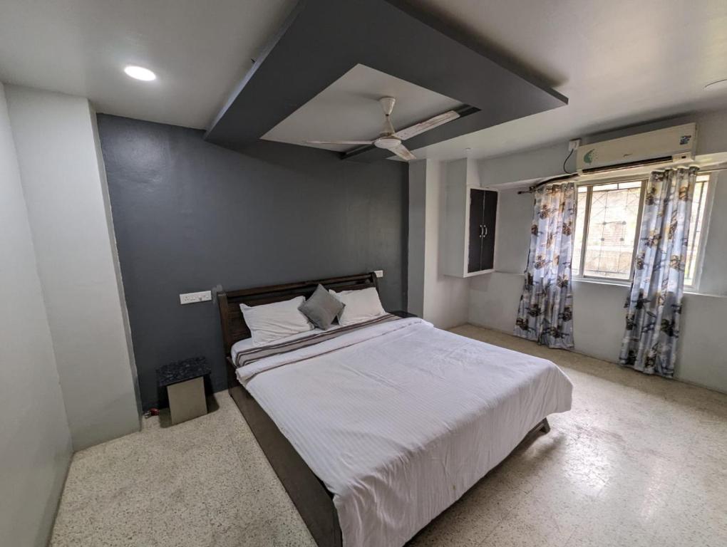 a bedroom with a large bed with white sheets at Swanky Sojourns Home Stay with AC bedroom in Kolhapur