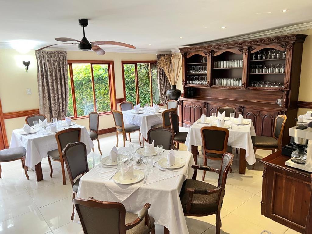a dining room with white tables and chairs at Limpopo Guest Manor in Polokwane