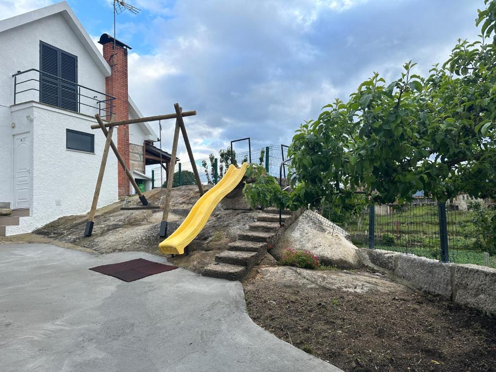 a playground with a yellow slide in front of a house at Casa do Cruzeiro in Aldeia