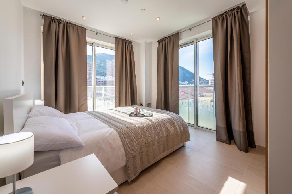 a bedroom with a bed and a large window at Bentley Holiday Apartments - West One in Gibraltar