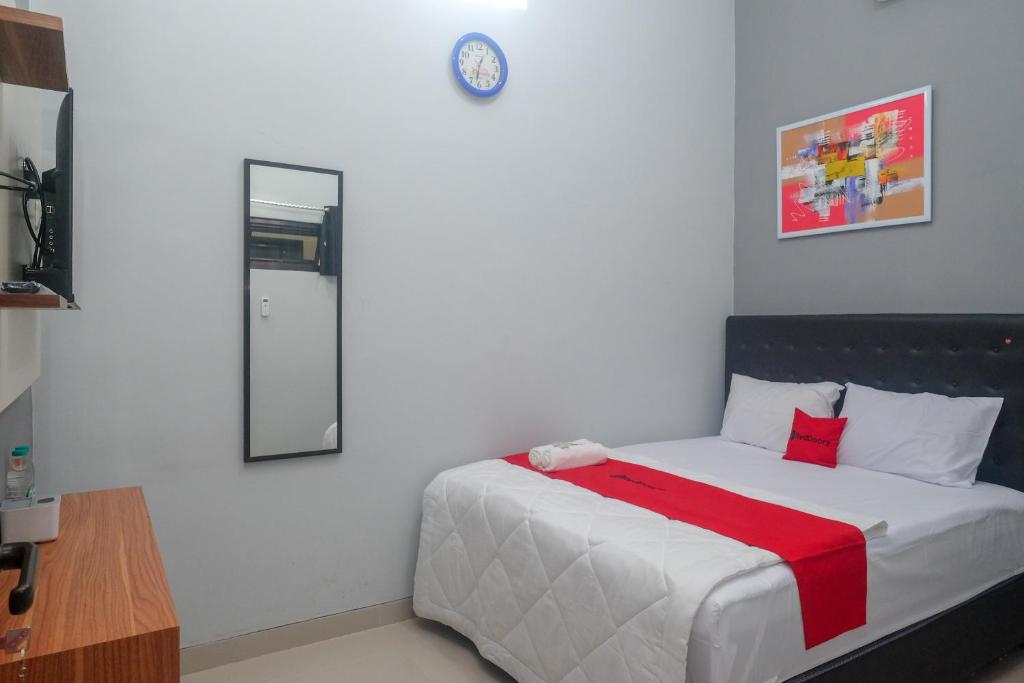 a bedroom with a bed with a red blanket on it at RedDoorz Near Dr Oen Solo Baru Hospital in Klaten