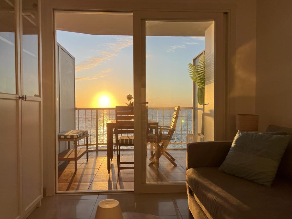 ein Wohnzimmer mit Blick auf einen Balkon mit einem Tisch in der Unterkunft Apartamento Primera línea playa in Las Palmas de Gran Canaria