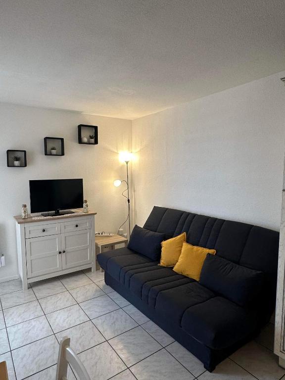 un salon avec un canapé bleu et une télévision dans l'établissement Appartement avec vue sur la mer, à Fleury