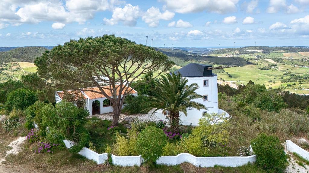 a white house on a hill with trees and bushes at NEW! Windmill in the midst of nature in Mafra