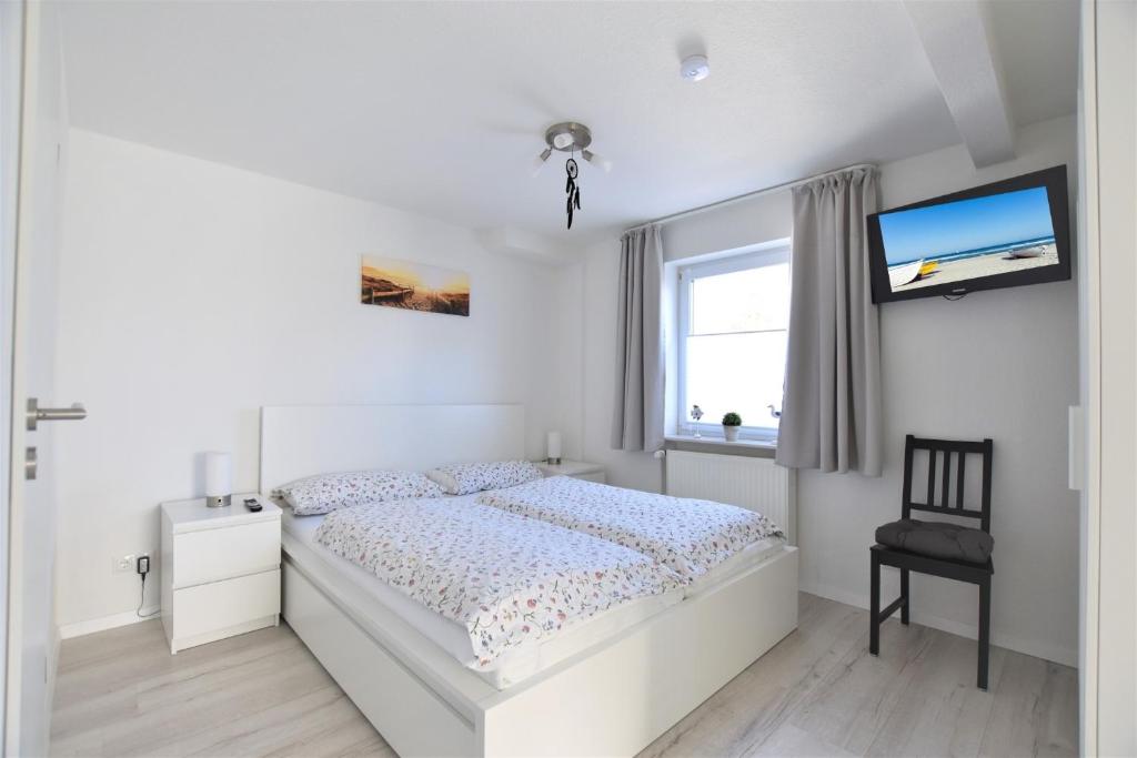 a white bedroom with a bed and a tv at Haus Prohl Whg1 in Dahme