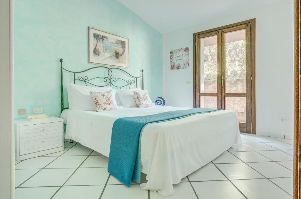 a bedroom with a large white bed with blue walls at VILLA MARIA - CAPO D'ORSO - HOME and MORE in Palau