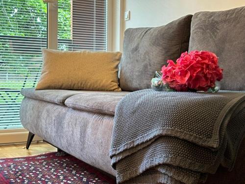 eine Couch mit einer Vase roter Blumen drauf in der Unterkunft Ljubljanica Apartment in Ljubljana