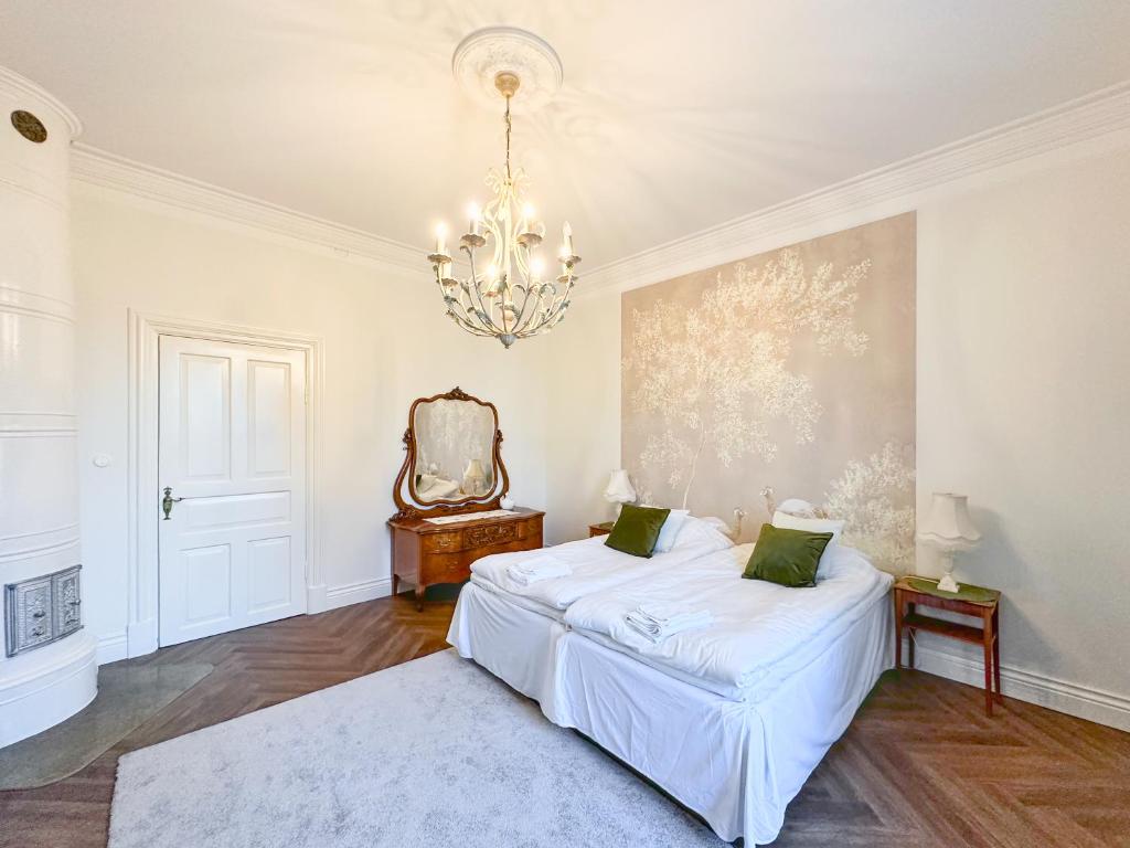 a white bedroom with a bed and a chandelier at Strandnäs Gård in Mariehamn
