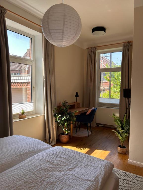 1 dormitorio con 1 cama, escritorio y 2 ventanas en Schöne Altbauwohnung direkt an der Kesselschleuse! en Emden
