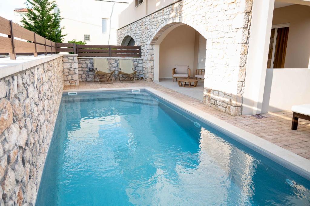 a swimming pool in a house with a stone wall at Lydia's Inn 2 with private pool in Melission