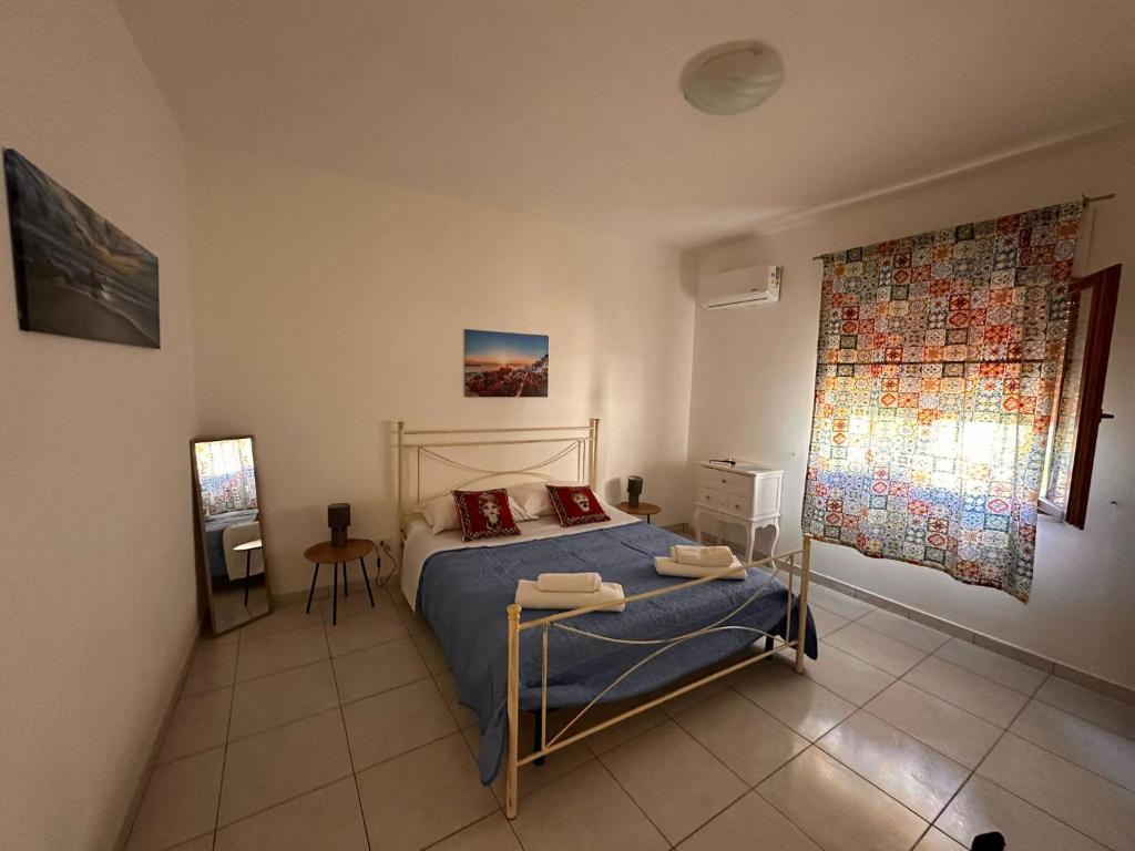a bedroom with a bed with blue sheets and a window at A Due Passi dal Centro in Favignana