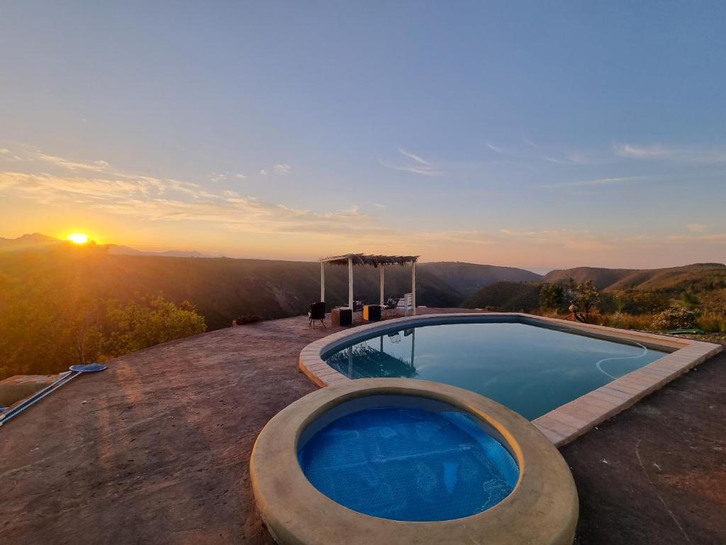 a swimming pool with a sunset in the background at Rainforest Ridge Eco Resort in The Crags
