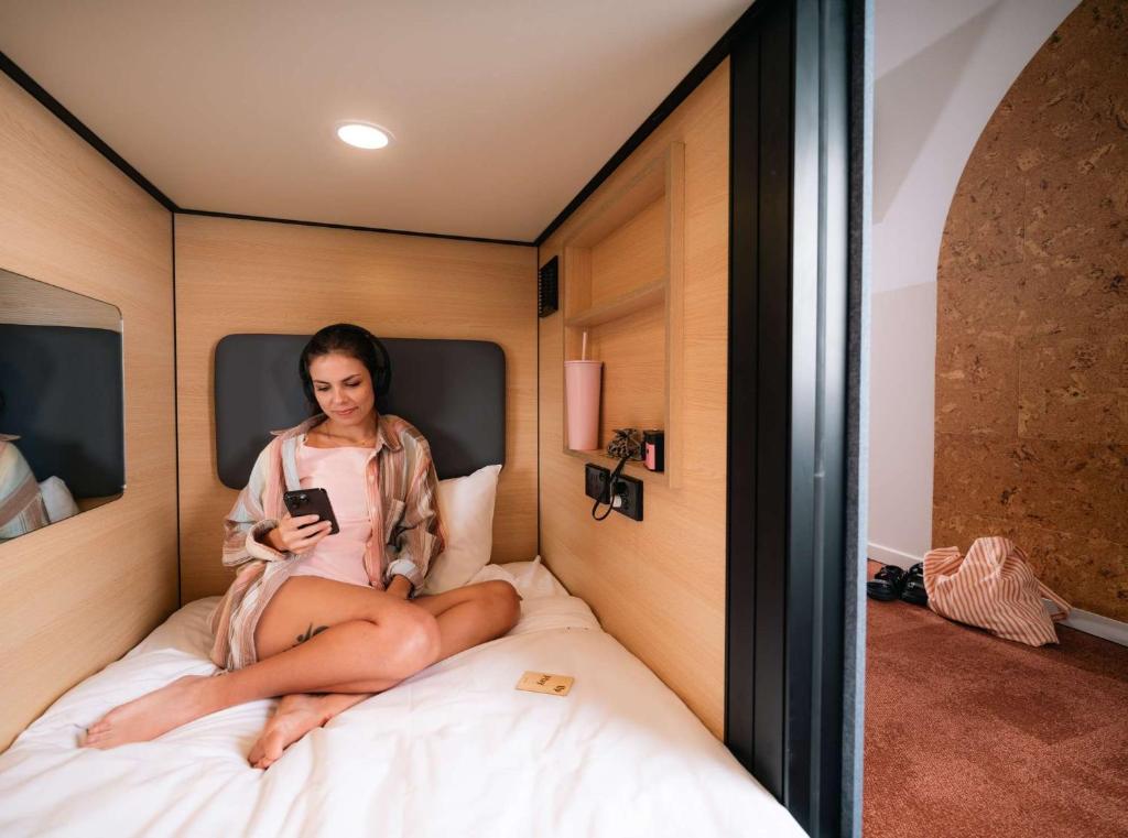 a woman sitting on a bed looking at her cell phone at LyLo Brisbane in Brisbane