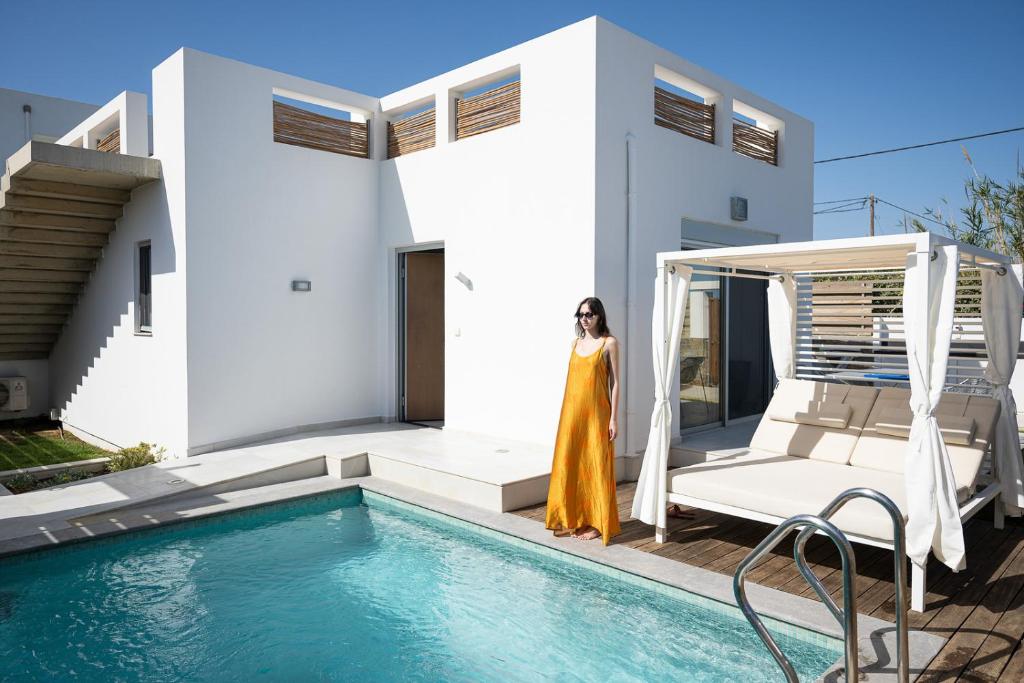 a woman in a yellow dress standing next to a pool at Thalasses in Adelianos Kampos